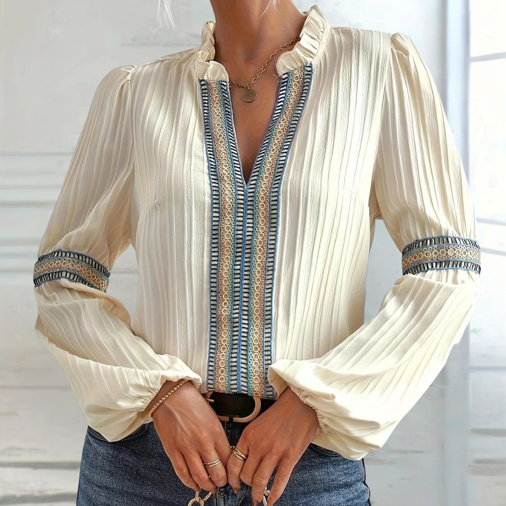 Elegante ivoorkleurige blouse met lange mouwen, geplooide stof en blauwe borduursels, perfect voor damesmode en casual chique outfits.