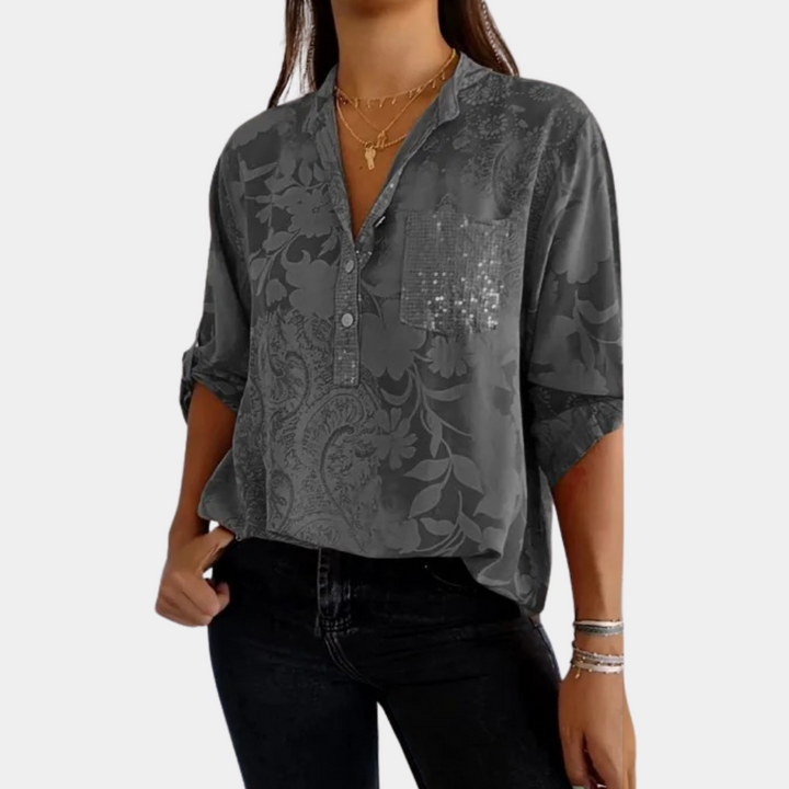 Damesblouse met verstelbare mouwen, grijs met bloemenpatroon en pailletten op borstzak, ideaal voor casual en stijlvolle outfits.