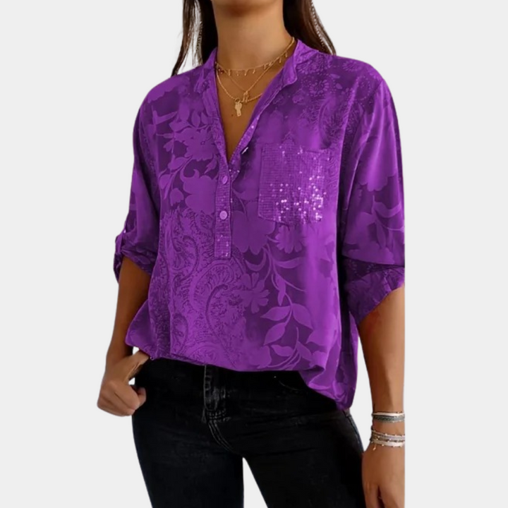 Paarse damesblouse met verstelbare mouwen, bloemenpatroon en borstzak, gedragen door model. Modieuze blouse voor casual en formele gelegenheden.