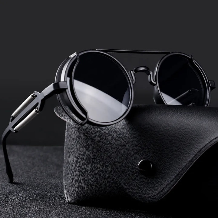Ronde zwarte zonnebril met metalen frame op een zwarte leren brillenkoker, stijlvolle unisex accessoire, modieuze zonnebrillen voor heren en dames.
