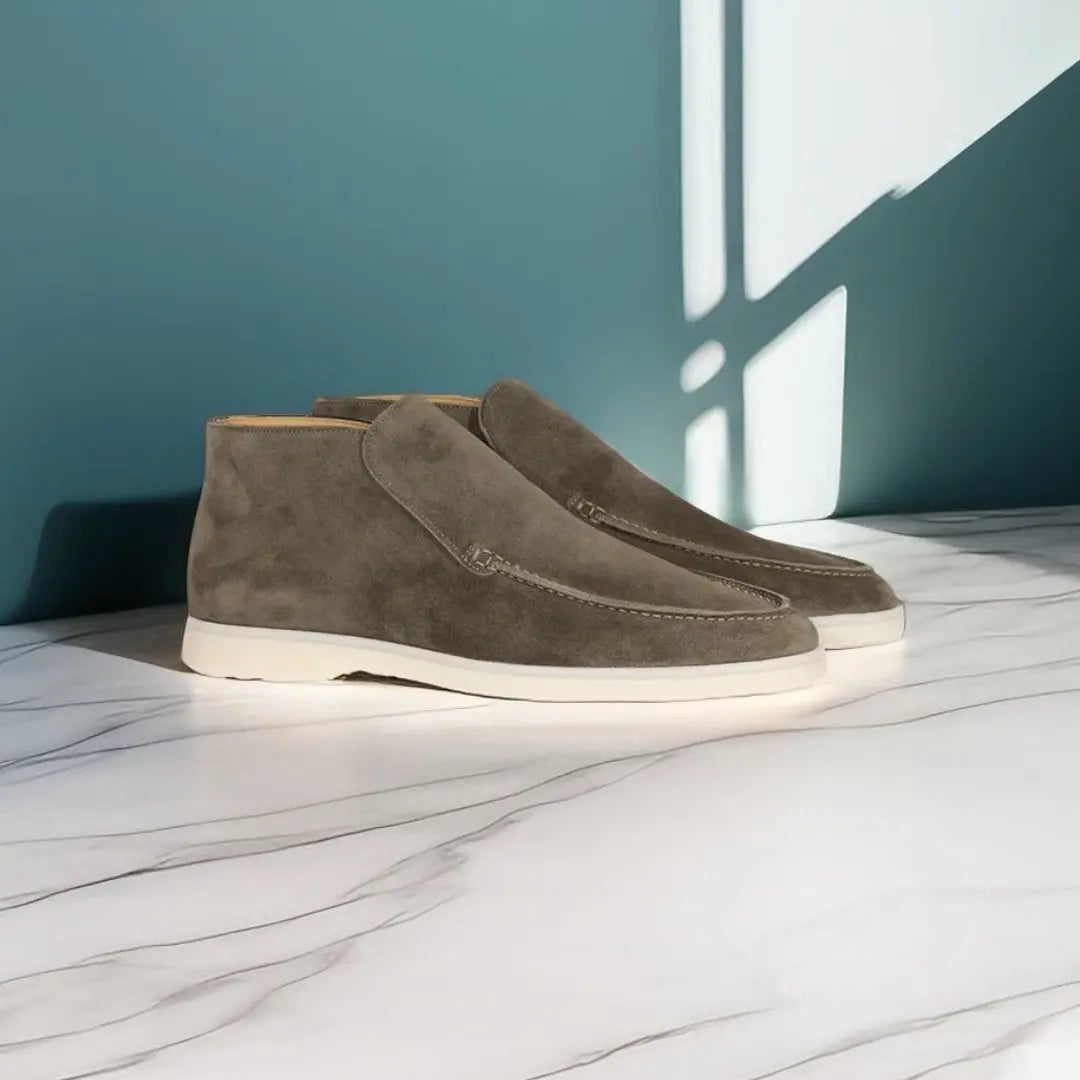 Grijze suède herenschoenen op marmeren vloer, tegen een blauwe muur. Stijlvolle casual schoenen, perfect voor moderne herenkleding.