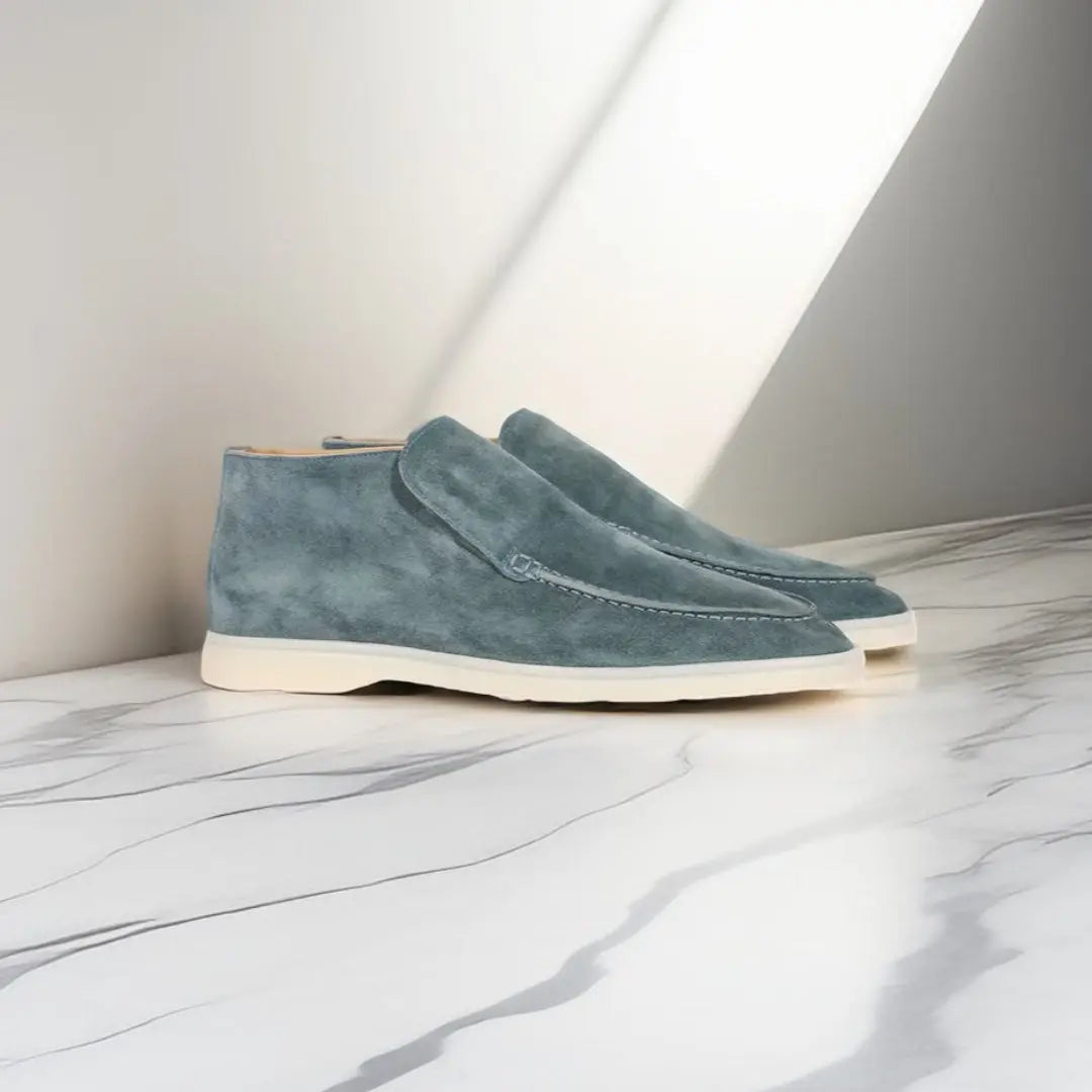 Blauwe suède herenschoenen met witte zolen op marmeren vloer, moderne en stijlvolle enkellaarzen, perfect voor casual en formele gelegenheden.