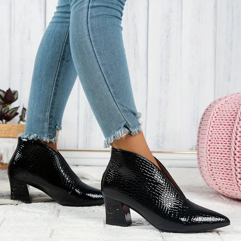 Dames enkellaarsjes met zwarte krokodillenprint, blokhak en puntige neus, gedragen met blauwe skinny jeans. Stijlvolle herfstmode.